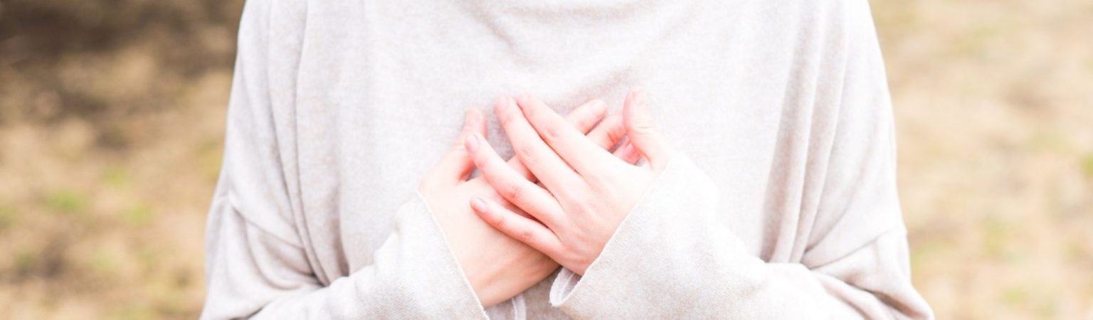 person standing with hands on heart, relaxed